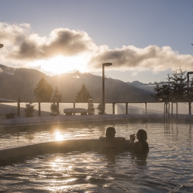 Bathers enjoying swimming at Ainsworth Hot Springs Resort with a view of Kootenay Lake.